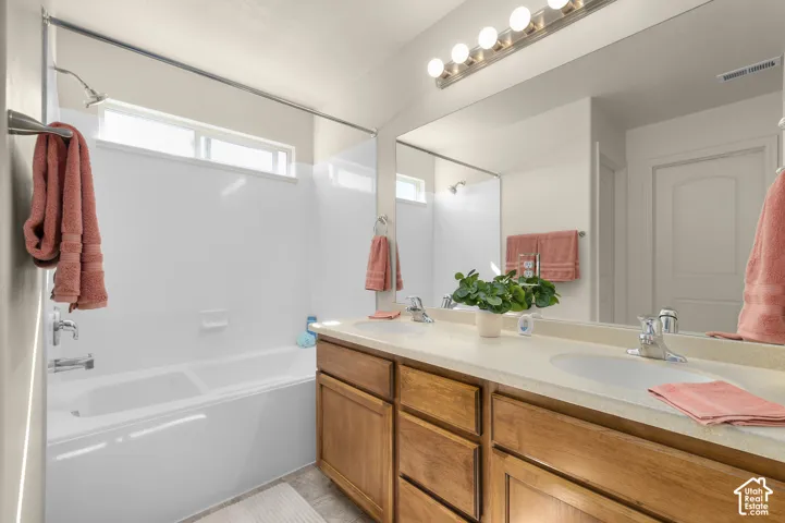 Primary Bathroom-Dual basin vanity with wood-finish cabinetry, a full-width mirror, and overhead lighting