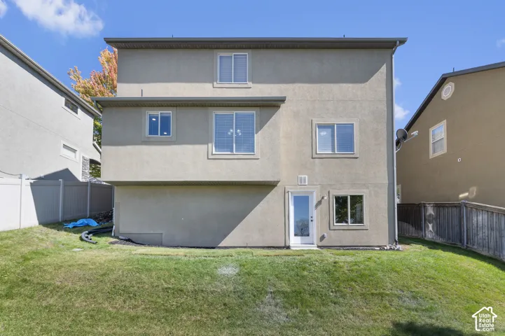 Walk-Out-Stucco exterior with multiple windows, a white glass-paneled door, and a green grass lawn