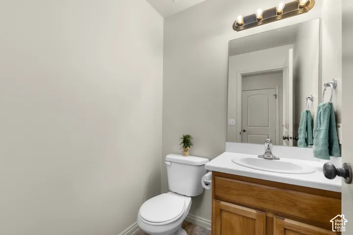 Half-Bath on Main-Vanity with wood-finish cabinetry, white countertop, and an oval sink