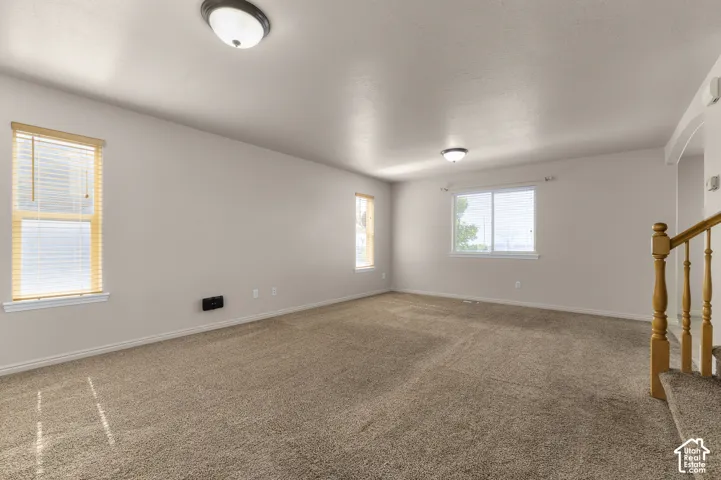 Expansive room featuring carpet flooring, multiple windows with blinds, and flush-mount ceiling lights