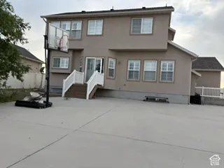 Stucco exterior with multiple windows, leading to a concrete patio with white railings