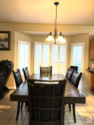 Bay window with white plantation shutters, tile flooring, and a bronze-finish chandelier
