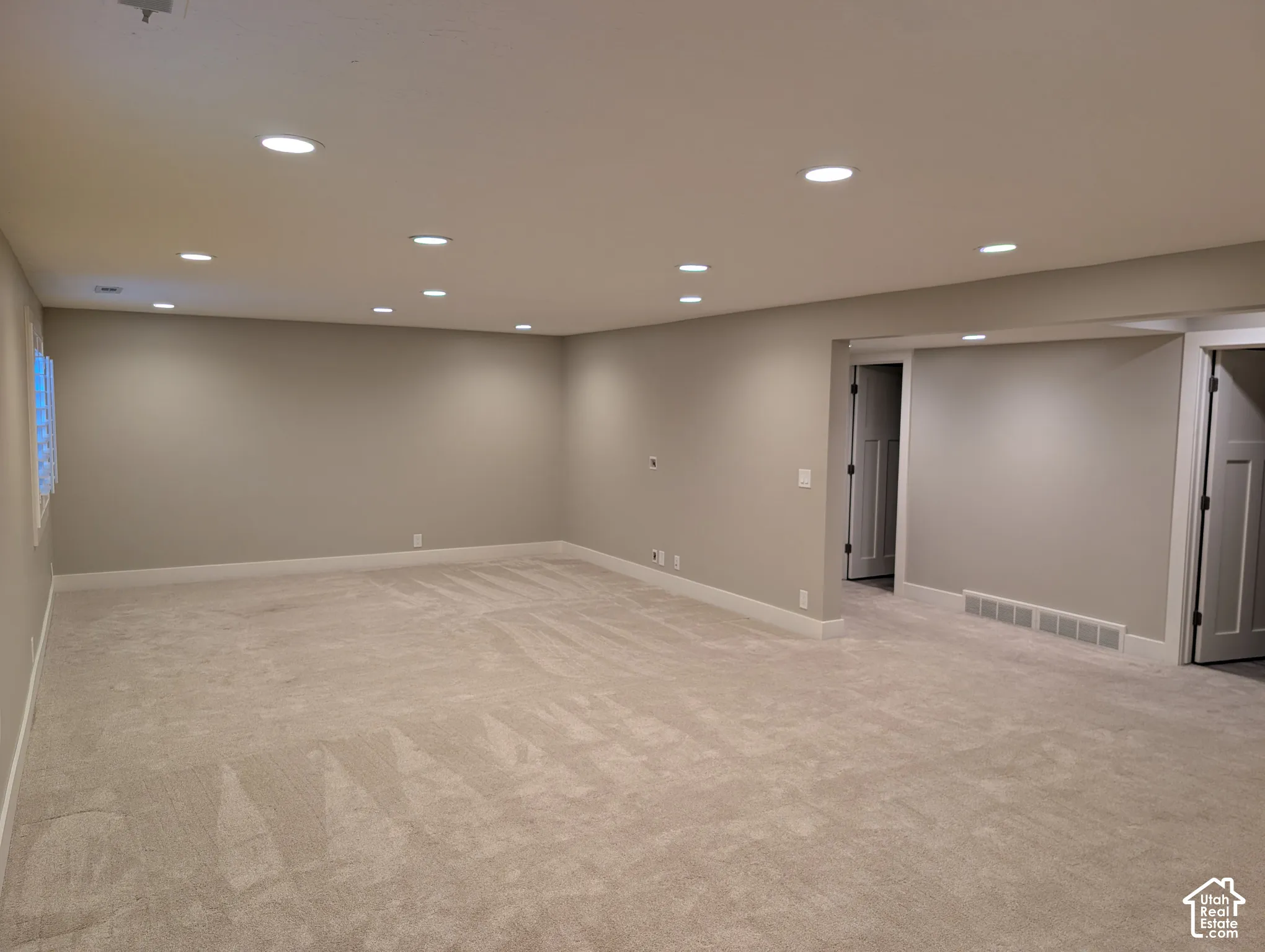 Expansive room featuring recessed lighting, light-colored carpeting, neutral wall tones, and white trim
