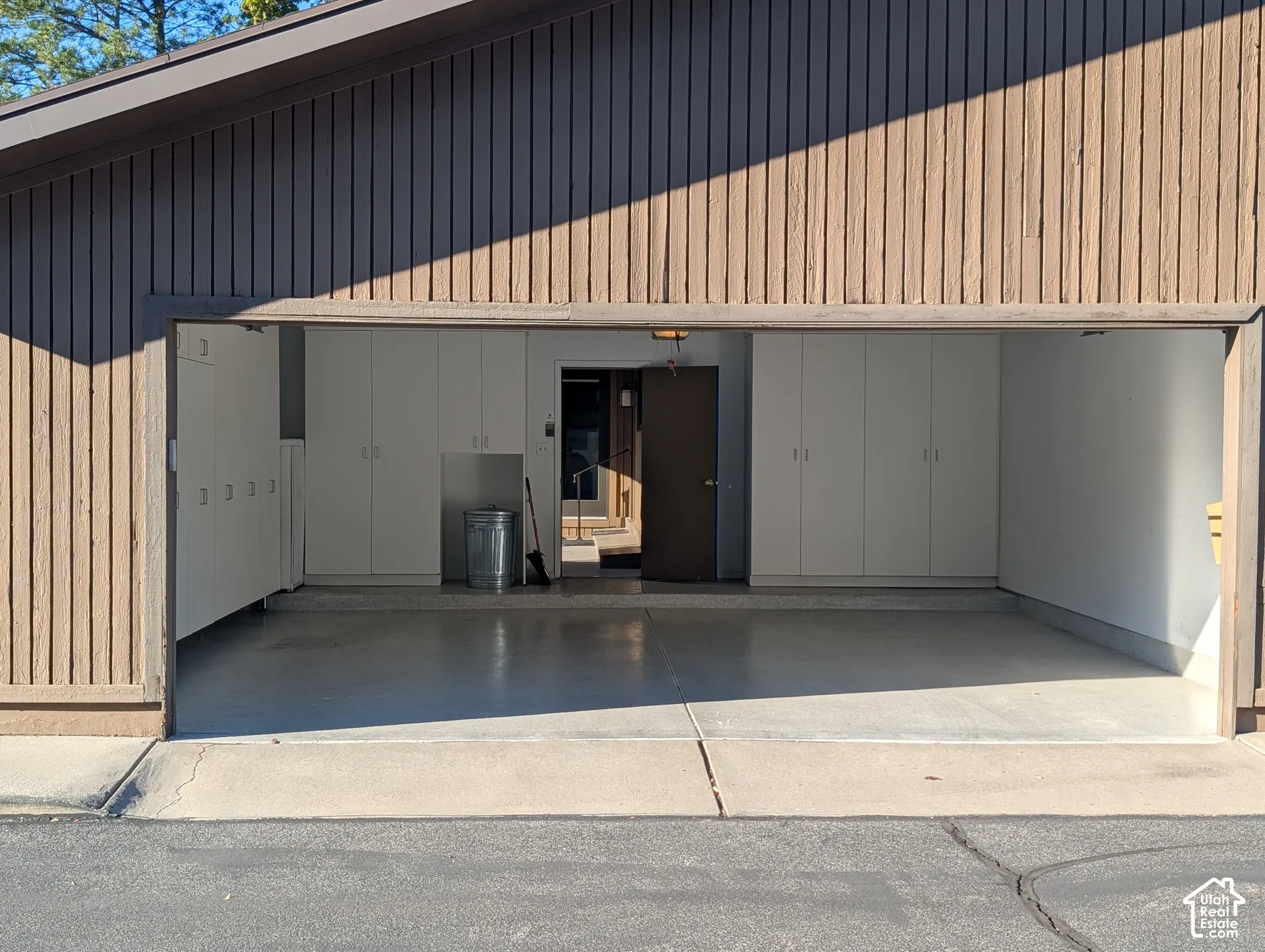 Garage featuring comprehensive built-in cabinetry, durable epoxy flooring, and vertical wood panel siding