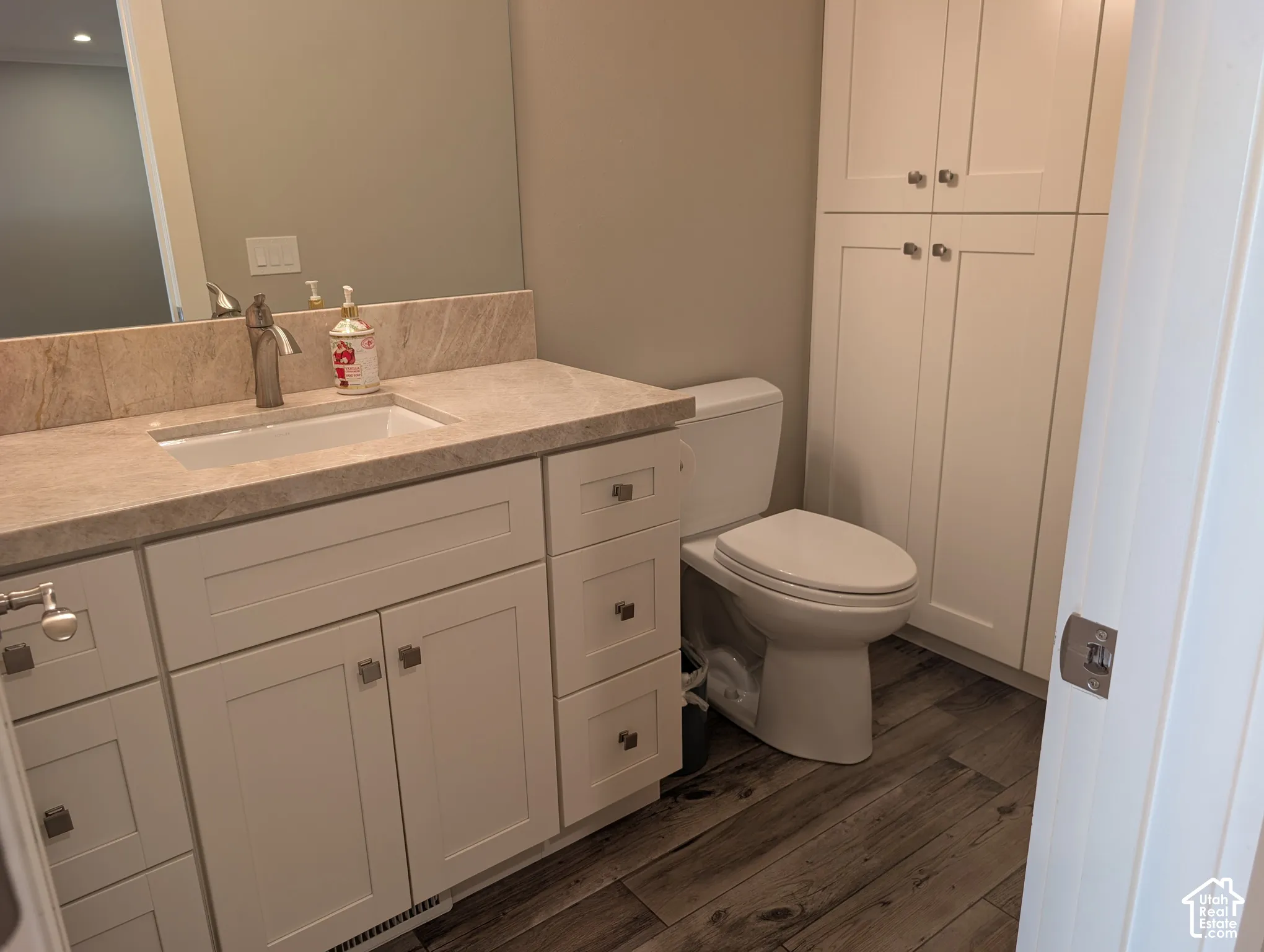 White shaker-style vanity with an undermount sink and a stone countertop