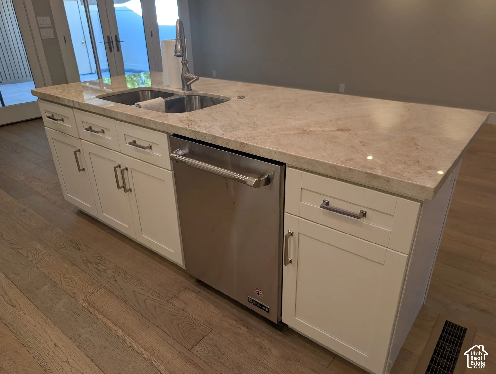 Center island with light-toned countertop, stainless steel sink, and integrated dishwasher