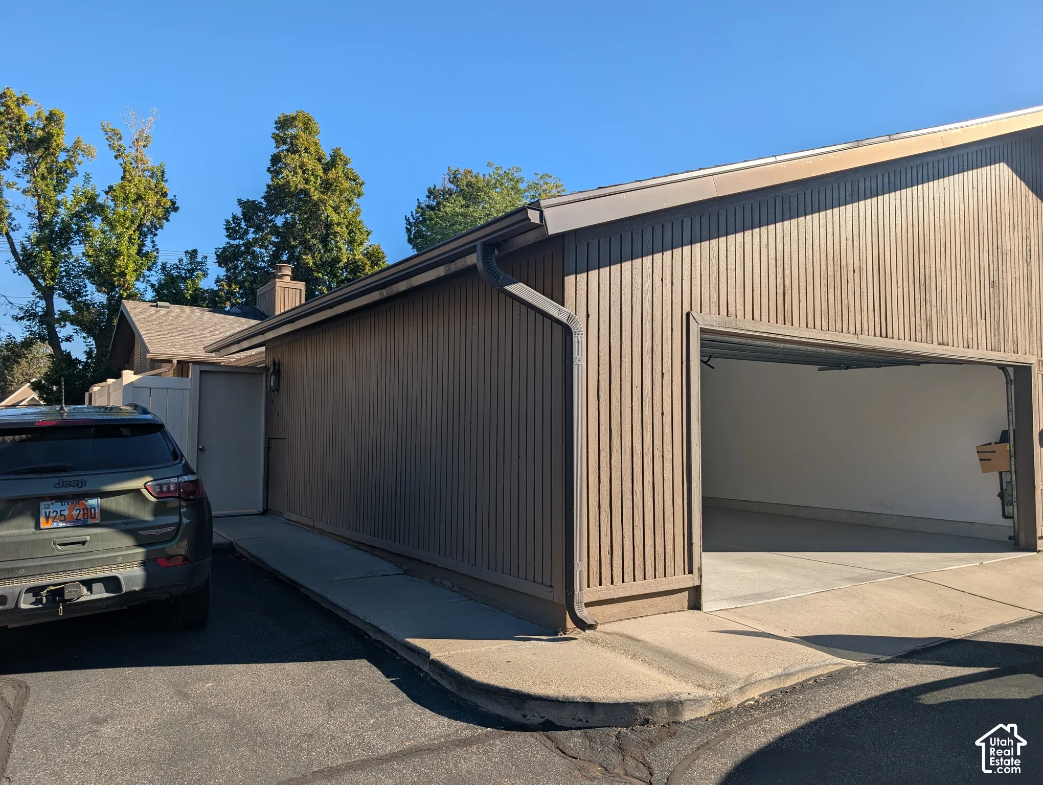 Attached two-car garage with vertical wood-finish siding, concrete floor, and an exterior light fixture
