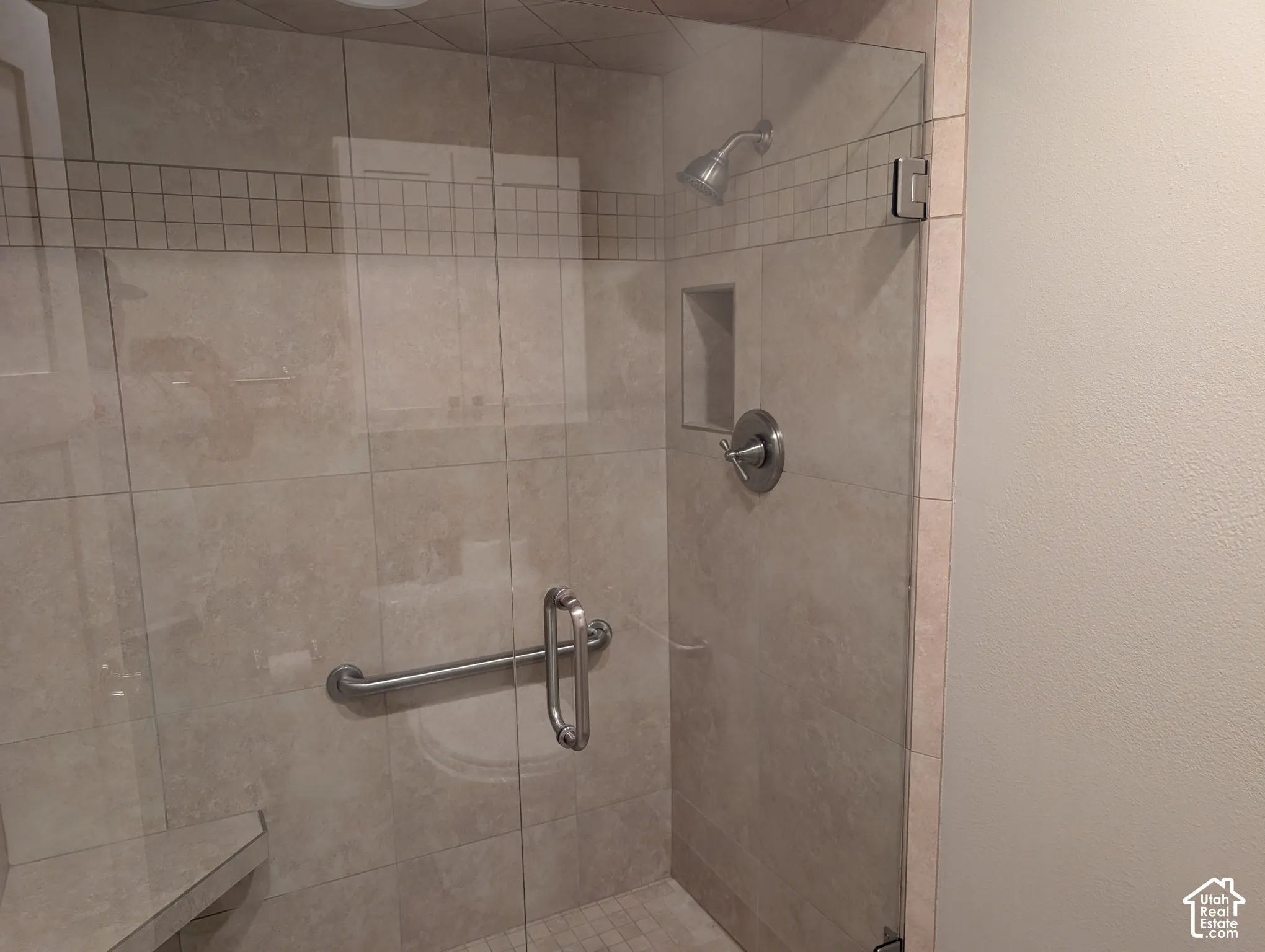 Glass-enclosed shower with ceramic tile walls, a built-in shower niche, and a chrome shower head and fixtures