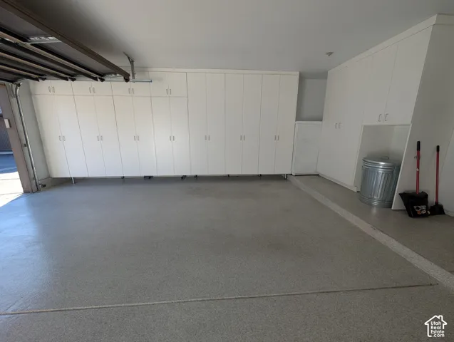 Expansive garage featuring extensive built-in white cabinetry, a durable epoxy-coated floor, and integrated overhead storage