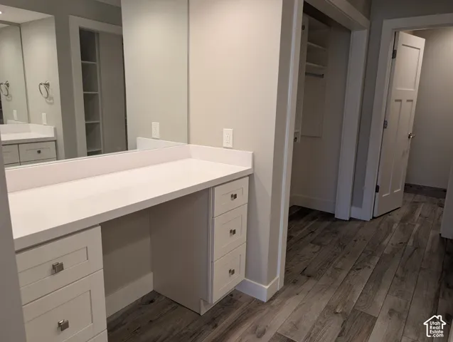 Built-in vanity with a white countertop and integrated sink, recessed lighting, and wood-finish flooring
