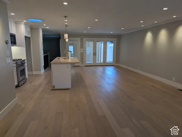 Expansive room with wood-finish flooring, recessed lighting, and crown molding