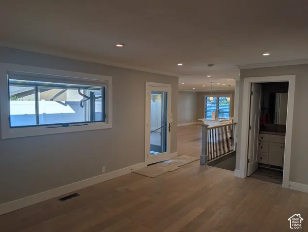 Light wood-finish flooring throughout, recessed ceiling lighting, crown molding, and a French door with glass panels