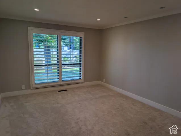 Window with plantation shutters, recessed lighting, crown molding, and carpeted flooring