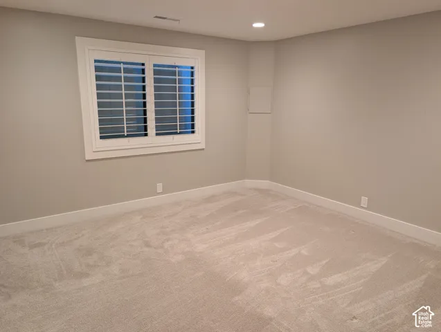 Window with white plantation shutters, recessed ceiling lighting, light-toned wall paint, white trim, and light-colored carpet flooring