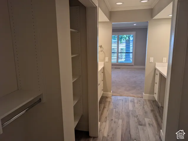 Built-in shelving, wood-finish flooring, recessed lighting, double vanity areas with white countertops, and window with plantation shutters