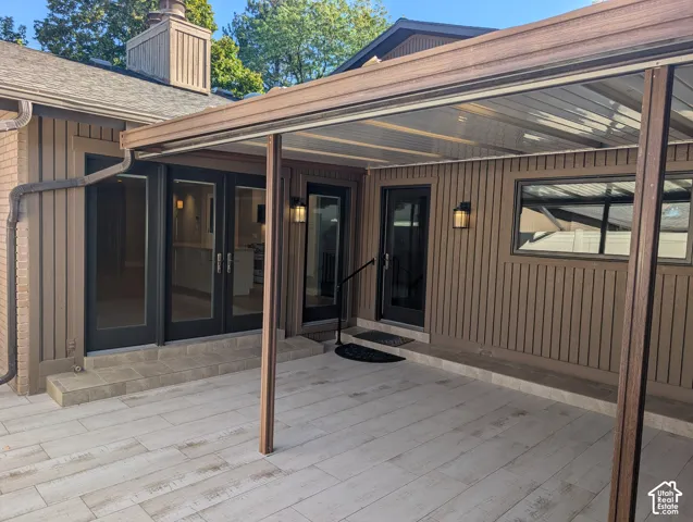 Expansive outdoor patio featuring light-toned plank-style tile flooring, a covered awning, and vertical siding