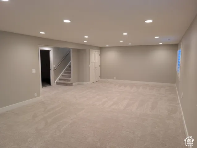 Spacious room with recessed lighting, light neutral-toned walls, light-toned carpeting, and a window with a white frame