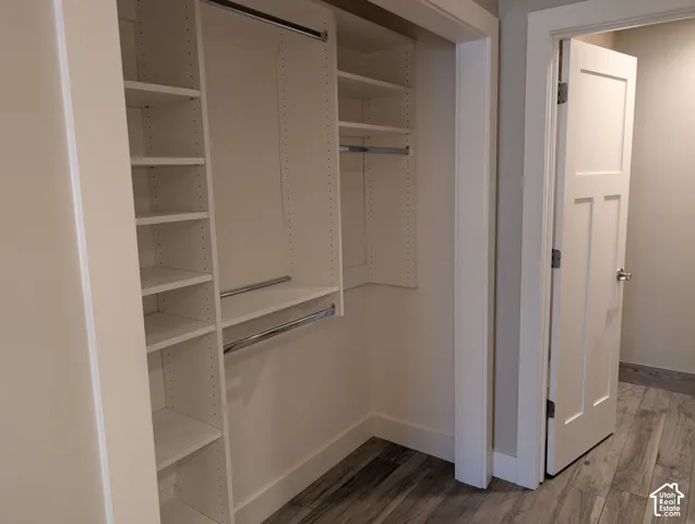 Built-in closet organization system featuring adjustable shelving, multiple hanging rods, and wood-finish flooring