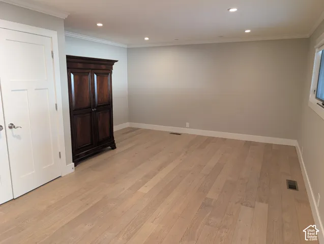 Wide plank wood-finish flooring, recessed lighting, crown molding, and a window for natural light
