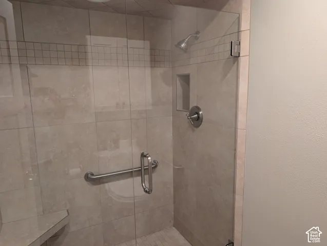 Glass-enclosed shower with ceramic tile walls, a built-in shower niche, and a chrome shower head and fixtures