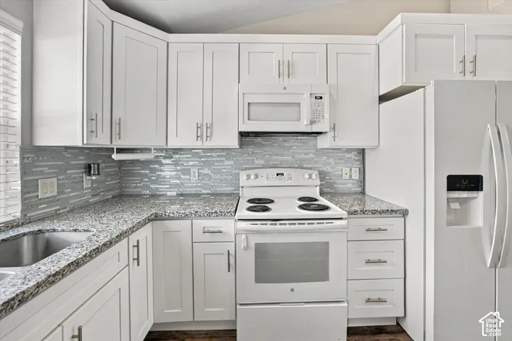 White shaker-style cabinetry with chrome hardware, granite countertops, tile backsplash, and a stainless steel sink