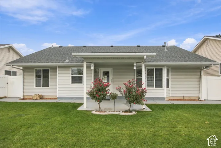 Rear exterior with a covered patio, vinyl siding, mature landscaping, a flat roof, and a fenced yard