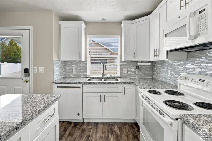 Kitchen featuring white cabinetry, granite-style countertops, mosaic tile backsplash, wood-finish flooring, and white appliances