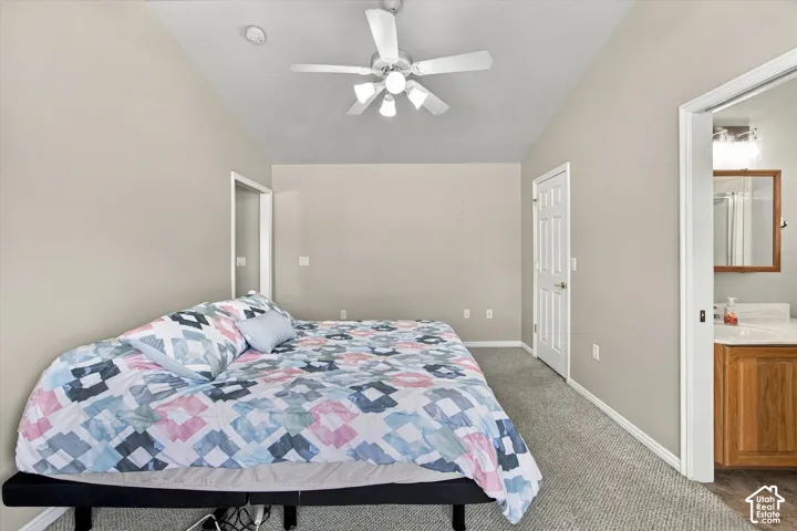 Vaulted ceiling with a ceiling fan, neutral wall paint, and gray carpeting