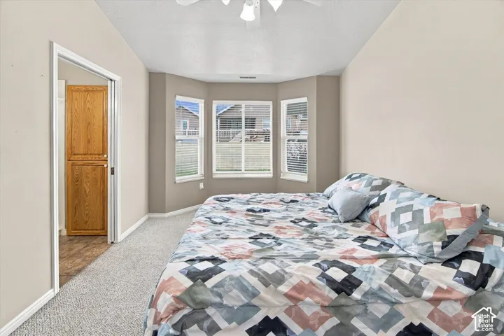 Recessed bay window, ceiling fan, neutral wall tones, carpeted flooring, and built-in wood cabinetry