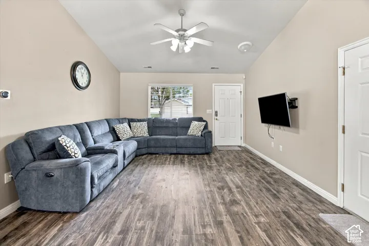 Vaulted ceiling with a ceiling fan, wood-finish flooring, and light-toned wall paint