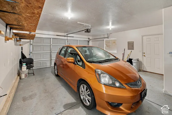 Attached garage featuring a panel garage door, built-in overhead shelving, and a secondary entry door
