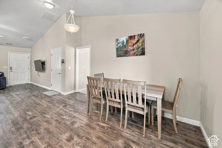 Vaulted ceiling, wood-finish flooring, two-panel interior doors, and a ceiling-mounted light fixture