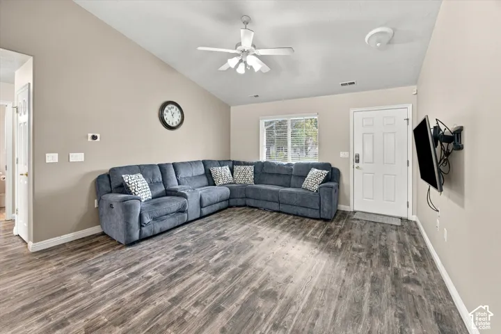 Vaulted ceiling featuring a ceiling fan, wood-finish flooring, and a white paneled entry door