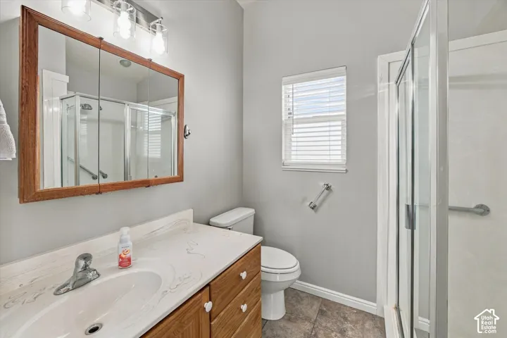 Bathroom featuring a wood-finish vanity with an integrated sink and light-toned countertop