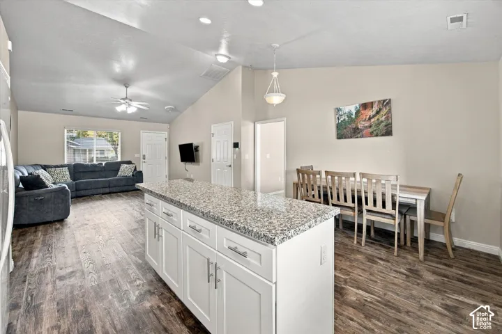 Open-concept living space with wood-finish flooring, vaulted ceilings, and recessed lighting