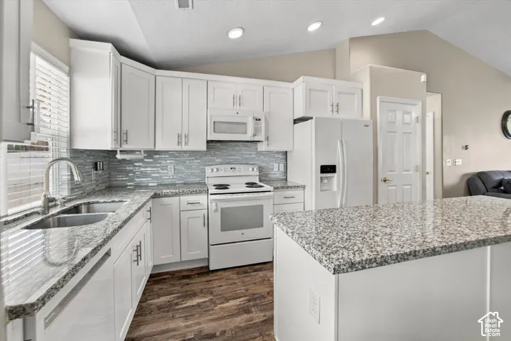 Kitchen featuring white cabinetry, light-toned countertops, a full suite of white appliances, a tiled backsplash, and recessed lighting