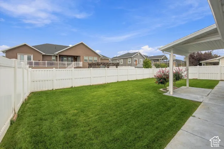 Expansive green lawn, white privacy fencing, covered patio, and mature landscaping