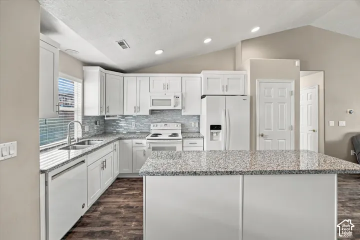 Kitchen featuring granite countertops, white cabinetry, a glass tile backsplash, wood-finish flooring, and recessed lighting
