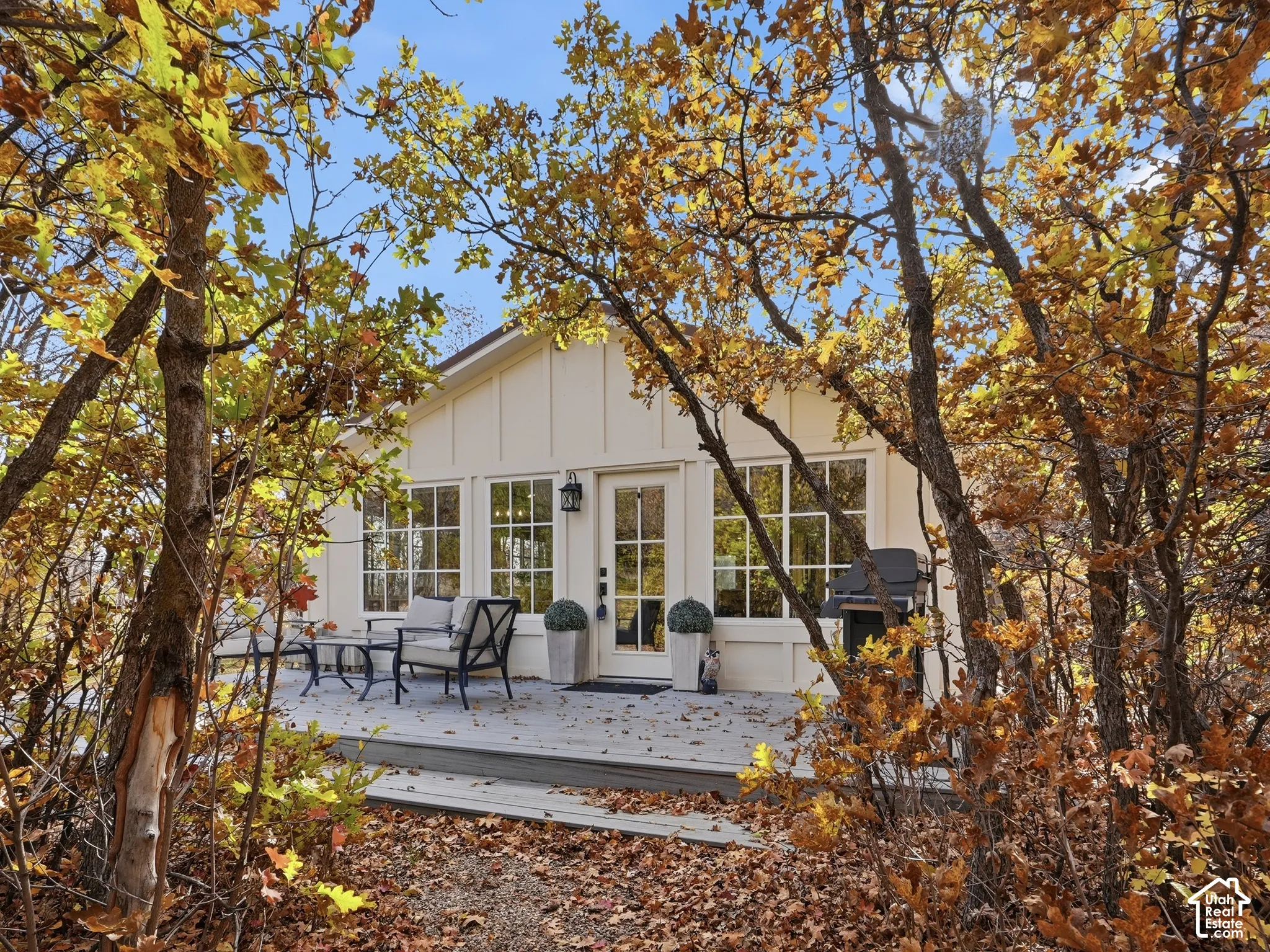 Exterior facade featuring board and batten siding, large grid-pane windows, a central glass-panel door, and a wooden deck