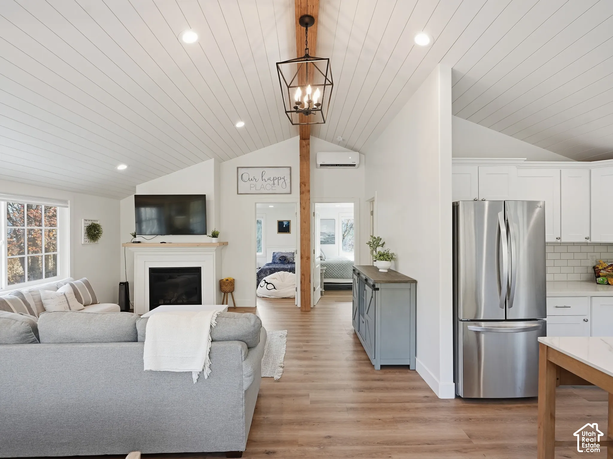 Vaulted shiplap ceilings with exposed timber detailing, wood-finish flooring, recessed lighting, industrial-style pendant fixture, and a fireplace with a wood mantel