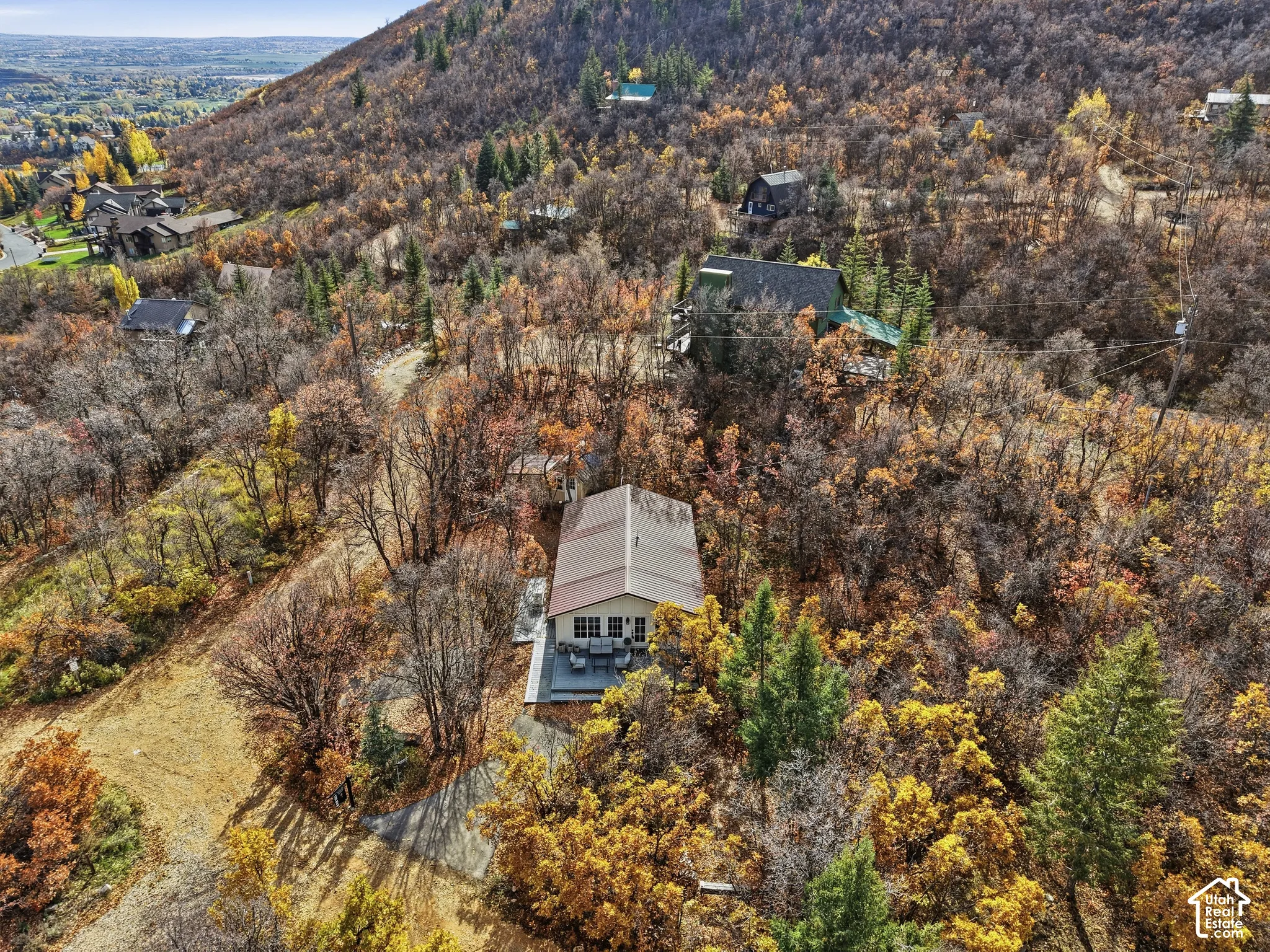 Elevated residential property featuring a metal roof, exterior deck, and wooded terrain