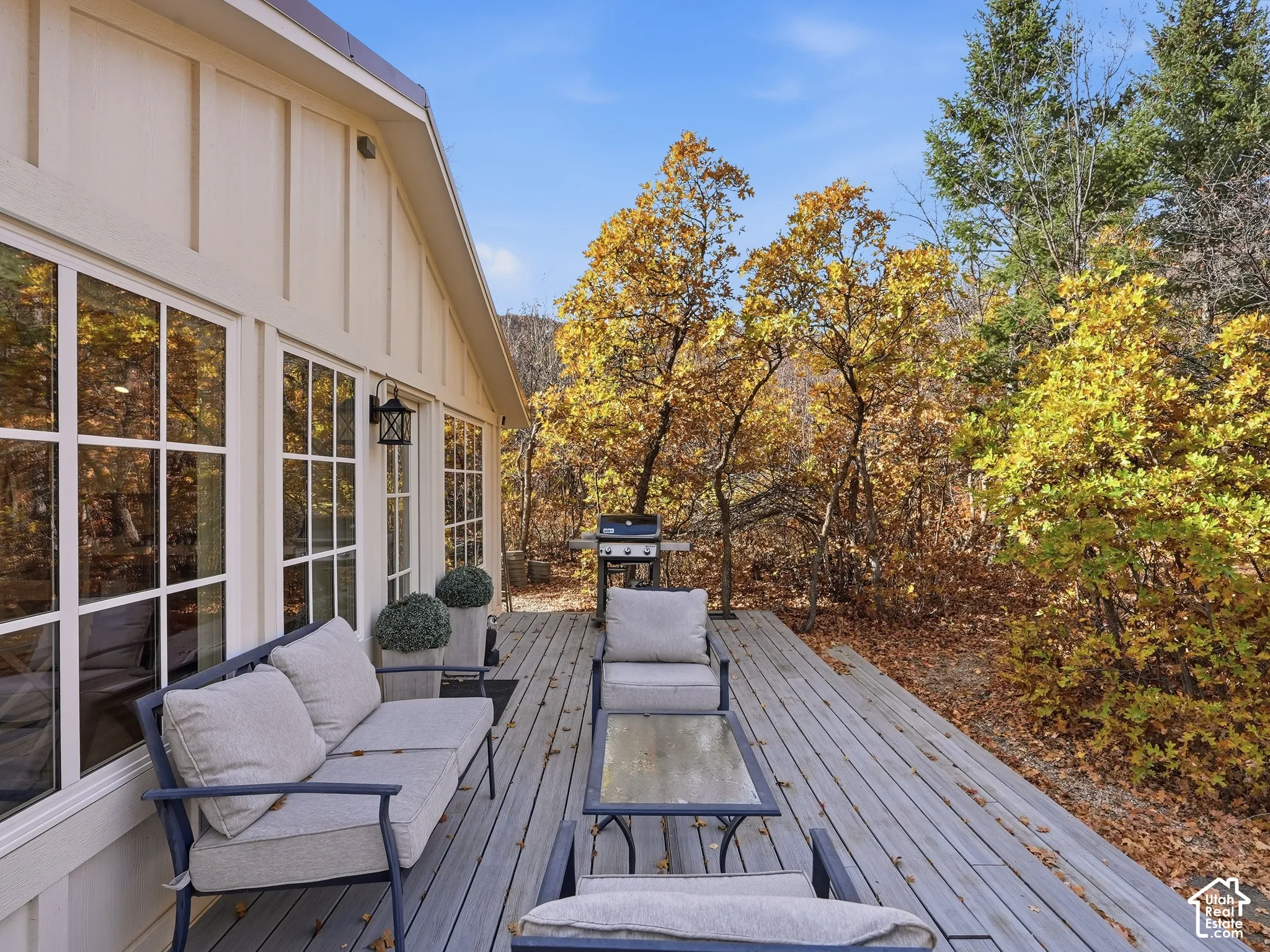 Spacious wood-plank deck featuring grid-pane window detailing, board-and-batten exterior siding, and exterior wall-mounted lighting
