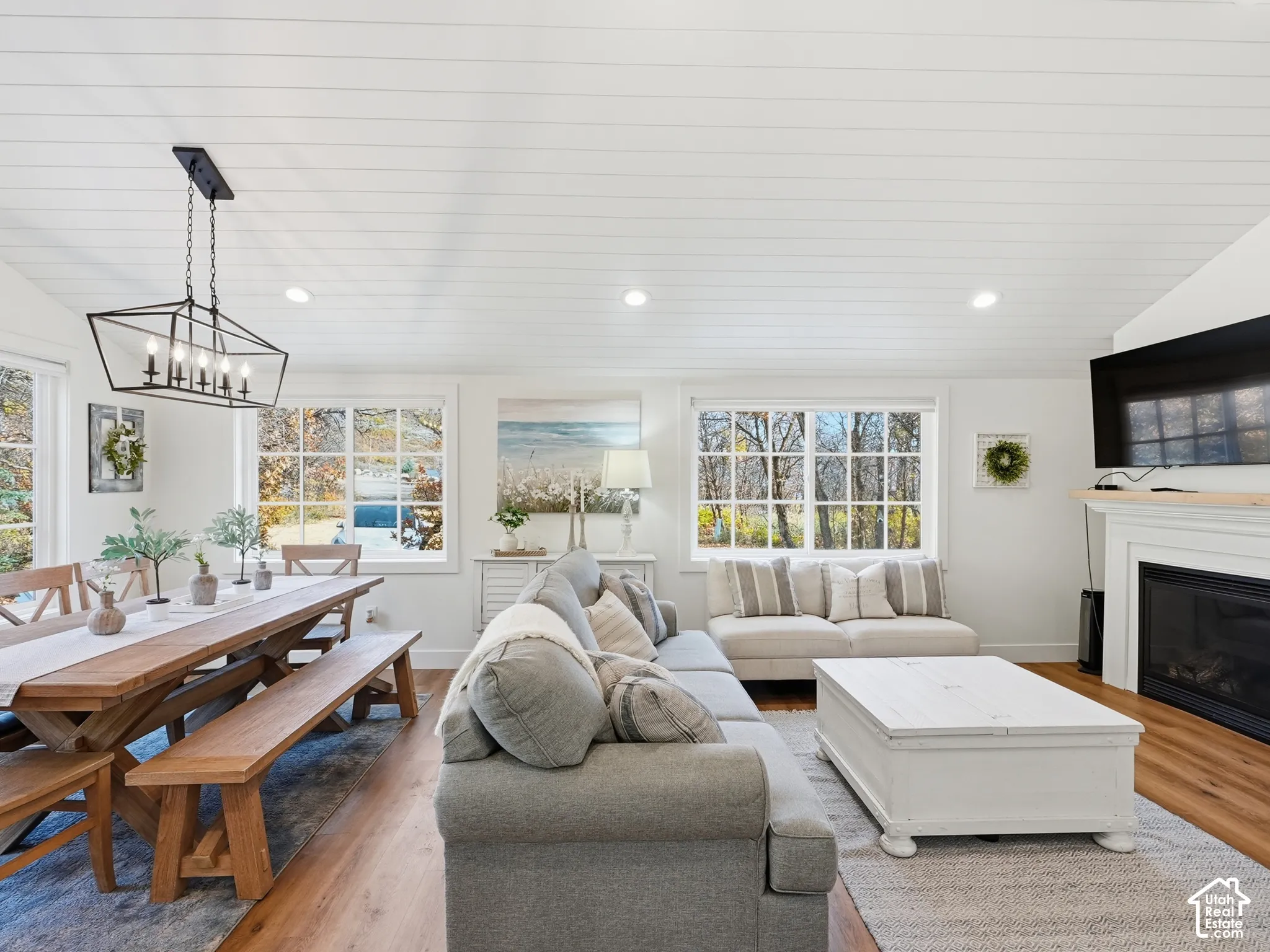 Vaulted shiplap ceiling, wood-finish flooring, fireplace with a mantel, and multi-pane windows