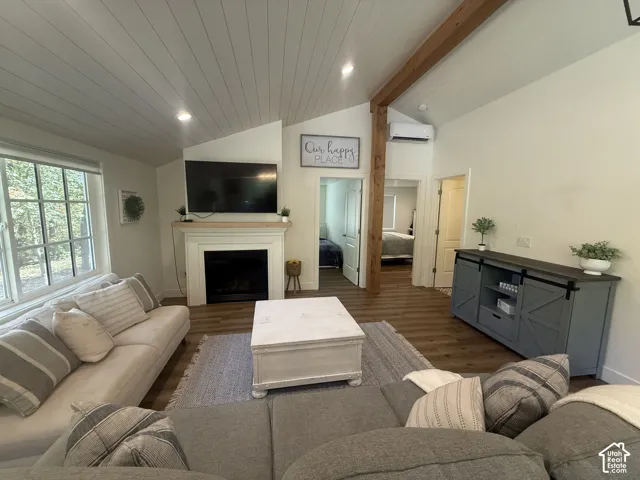 Vaulted ceiling with wood-finish planks, exposed wood beam, recessed lighting, and a white fireplace with a natural wood mantel