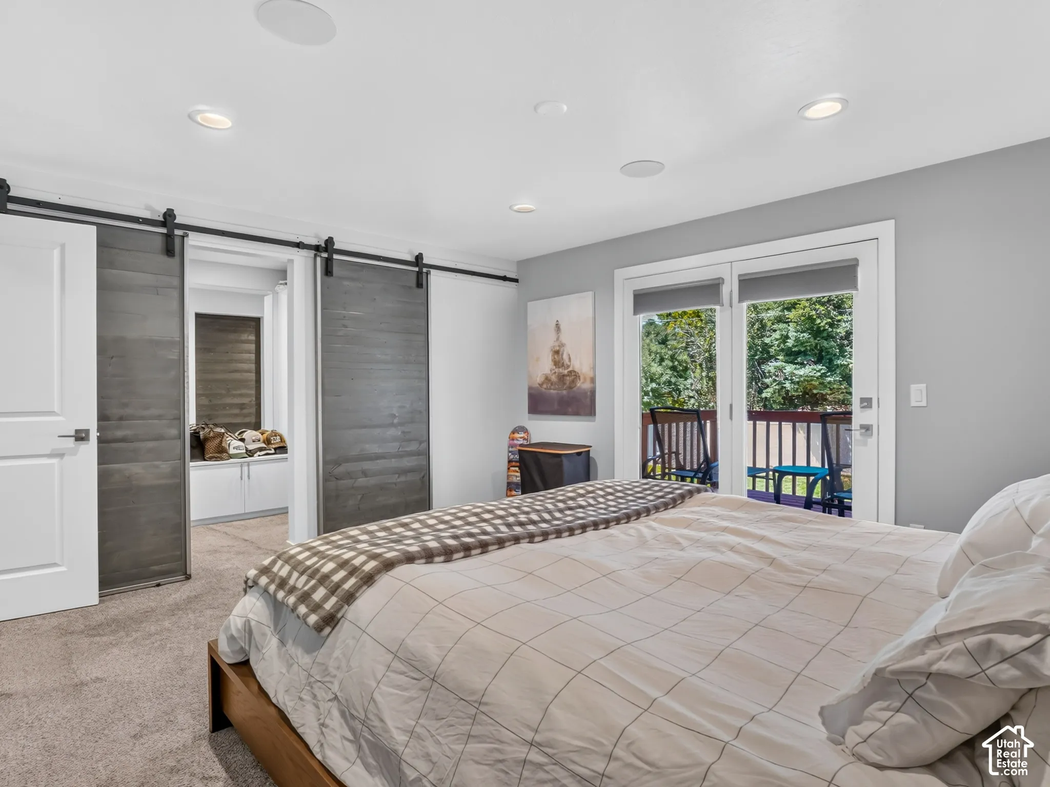 Recessed lighting, wood-finish barn doors, white trim, sliding glass door, and outdoor balcony with dark railing
