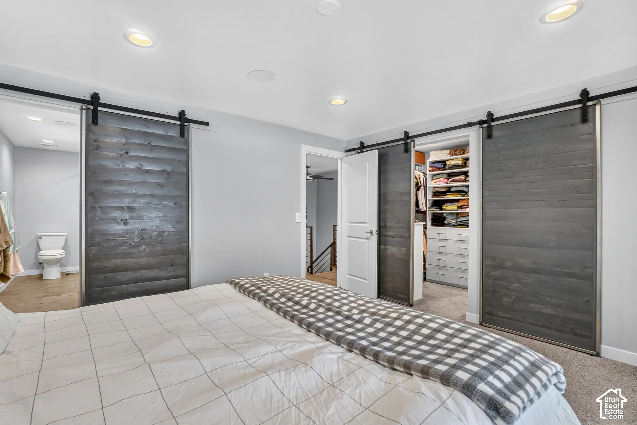 Recessed lighting, wood-finish barn doors, built-in closet organization, and light gray wall paint