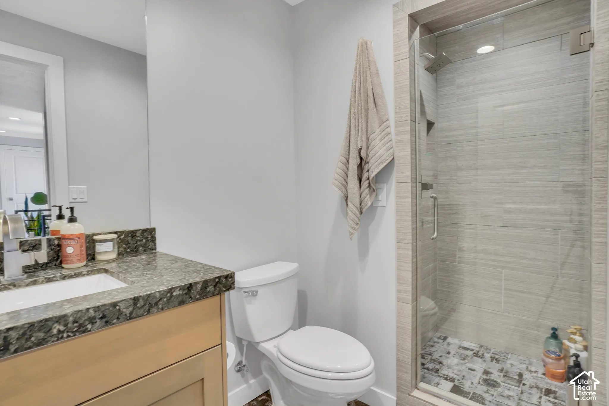 Vanity with granite-style countertop, undermount sink, and wood-finish cabinetry