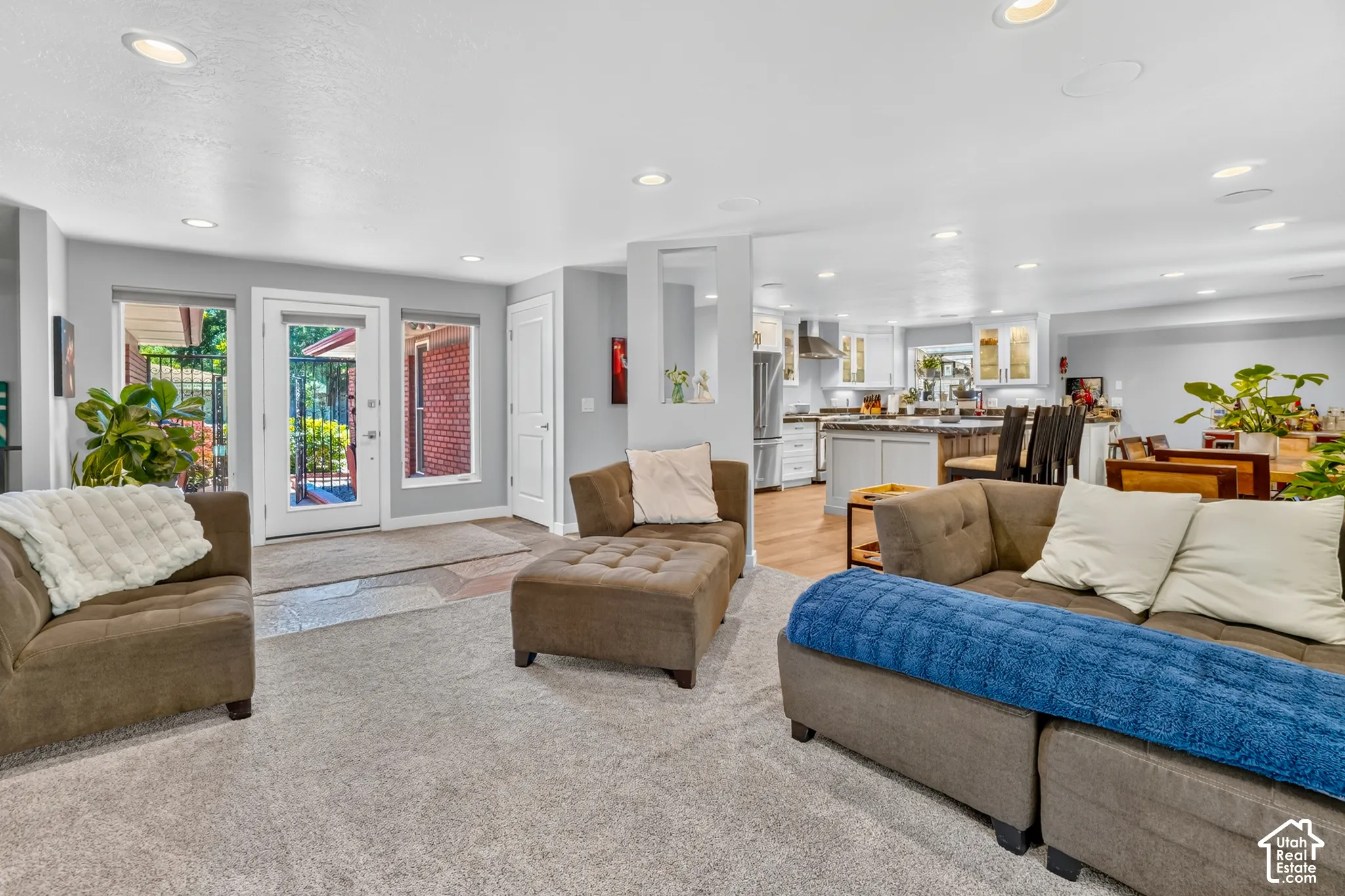 Recessed lighting, light gray carpet, and a kitchen with light-finish cabinetry, stainless steel appliances, and wood-finish flooring