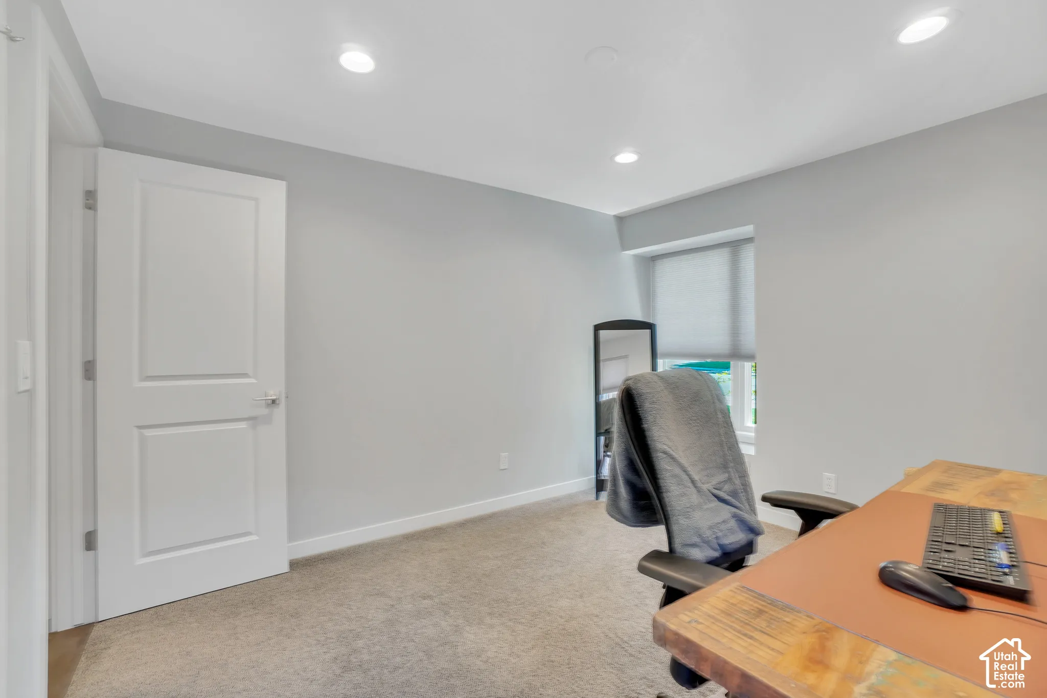 Recessed lighting, light gray wall paint, carpeting, white trim, and a window with a roller shade
