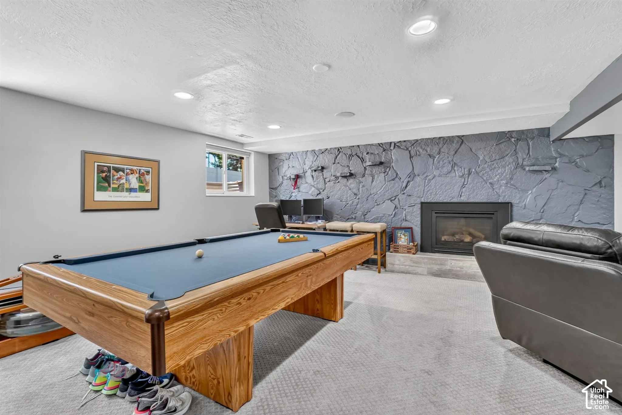 Recessed lighting illuminates the space, complemented by a stone-finish accent wall featuring a fireplace with a hearth